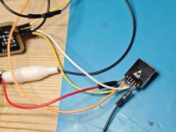 Small circuit board with connected wires on a blue work mat