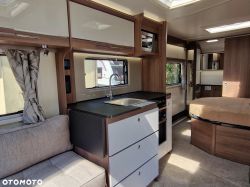 Interior of a modern camper trailer with a kitchenette and bedroom.