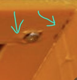 Close-up of orange plastic housing with surface flaws and arrow markers