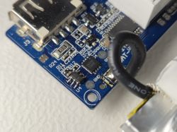 Zbliżenie na niebieską płytkę drukowaną z portem USB i widocznymi komponentami elektronicznymi oraz przewodem.
