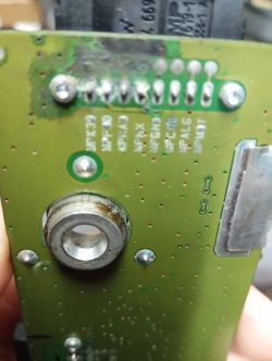 Close-up of PCB with corroded area near pin headers and labeled signal names