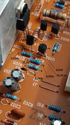 Zbliżenie na płytkę drukowaną z elementami elektronicznymi, takimi jak rezystory i tranzystory, z zaznaczonymi napięciami.