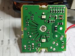 Widok od spodu zielonej płytki drukowanej z przylutowanymi elementami elektronicznymi i zaznaczonymi miejscami ścieżek zasilania.