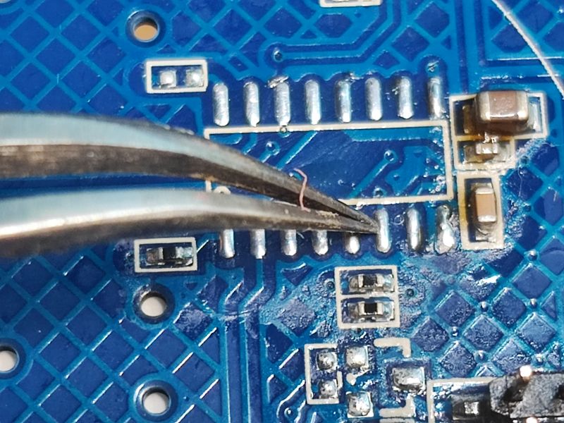 PCB with Wire at Solder Pads PCB with a thin wire at solder pads, held by tweezers.