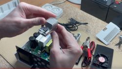 Osoba trzymająca radiator w rękach nad rozbudowywaną elektroniką.