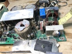 Wnętrze zasilacza z wyraźnymi śladami zabrudzenia i korozji, widocznymi cewkami oraz aluminiowym radiatorem.