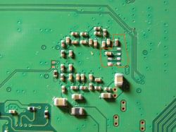 Zbliżenie na płytkę drukowaną z zaznaczonymi elementami elektronicznymi.