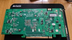 Tył zielonej płytki PCB karty graficznej z widocznym złączem PCIe i śrubami mocującymi