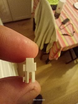 Złącze 3-pinowe trzymane w palcach na tle wnętrza z kolorowym obrusem.