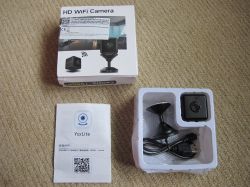 HD WiFi Mini Spy Camera Set with Accessories HD WiFi mini camera set including packaging, user manual, the camera, mount, and USB cable on a light carpet.