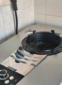 Ekspres do kawy z otwartym pojemnikiem na ziarna i widoczną parą wodną