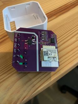 Circuit board with a purple circuit and electronic module on a wooden surface.