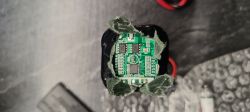 Zbliżenie na baterię z układami elektronicznymi i osłoną z zielonego materiału.