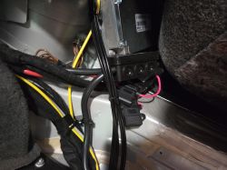 Instalacja elektryczna w aucie: wiązki kabli i dwa czarne uchwyty bezpieczników przy module