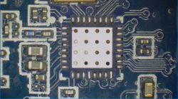 Close-up of a printed circuit board with a chip module and soldering traces.