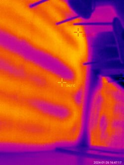 Termograficzne zdjęcie ściany z widocznymi różnicami temperatury i meblami w kadrze