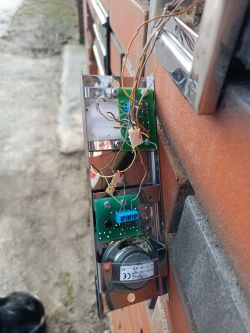 Zbliżenie na otwarty panel domofonu z widocznymi kablami i obwodami.