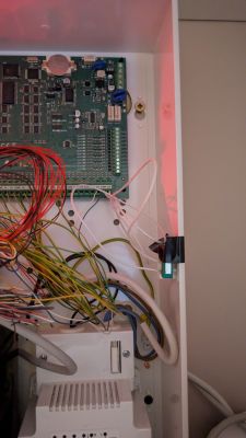 Płyta główna systemu alarmowego z podłączonymi przewodami i zasilaczem