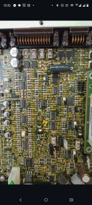 Close-up of a PCB with SMD components, fuses, and spring contacts along the top edge