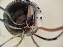 Wnętrze puszki elektrycznej z wystającymi kablami.