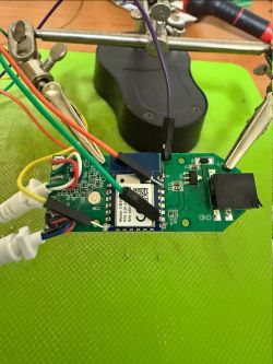 PCB with communication module, wires, and soldering helping hand clamp
