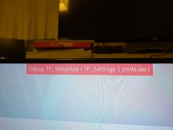 Na ekranie telewizora Samsung widoczne jest czerwone okno debugowania Debug: TP_SetupApp > TP_Settings (cm96.lee).