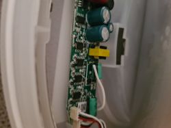 Interior of an electronic lamp with visible circuit board and soldered wires.