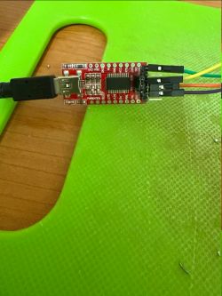 FTDI USB to TTL module with jumper wires on green textured mat