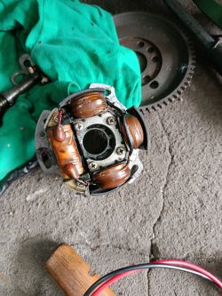 Stojan magneta motocykla z miedzianymi uzwojeniami, leżący na szmatce na podłodze warsztatu