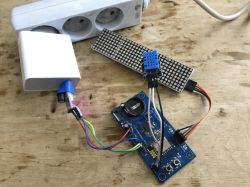 ESP module with DHT11 sensor, LED matrix, and USB power supply on a wooden table