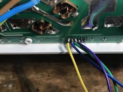 Close-up of a power strip PCB with multicolored wires soldered to several pins.