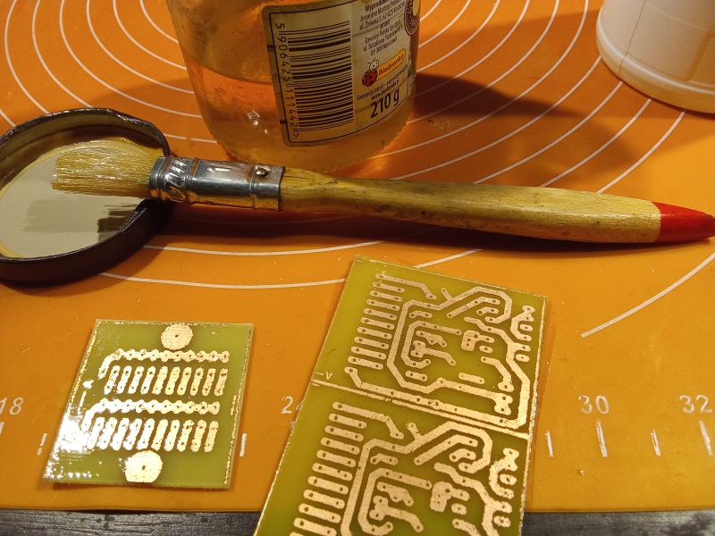 Printed circuit boards, brush, and jar on an orange mat.