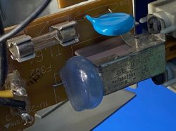 Zbliżenie płytki PCB z bezpiecznikiem, niebieskim dyskiem i elementami elektronicznymi