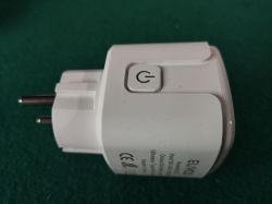 White smart plug with EU prongs and a power-symbol button on a green background