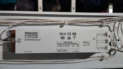 Moduł elektronicznego statecznika TRIDONIC w oprawie świetlówkowej, z widocznym okablowaniem i zaciskami
