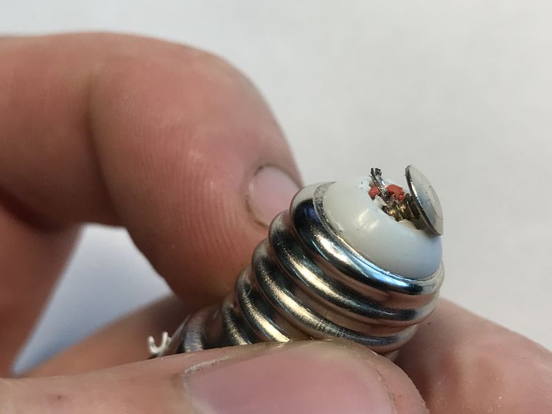 LED Bulb Base Disassembly Process Close-up of an LED bulb base with exposed wires after contact plate removal.