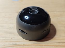 Dome-style security camera on wooden table Black dome security camera on wooden surface with round lens on top