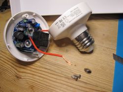 Open Light Bulb Adapter Open light bulb adapter with visible electronic components and screws on a wooden surface.