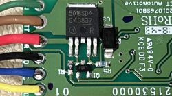 Zbliżenie na płytkę drukowaną z podzespołami elektronicznymi i kolorowymi kablami.