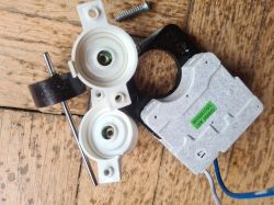 Zdjęcie pokazuje rozebrany mały silniczek elektryczny z elementami mocującymi.