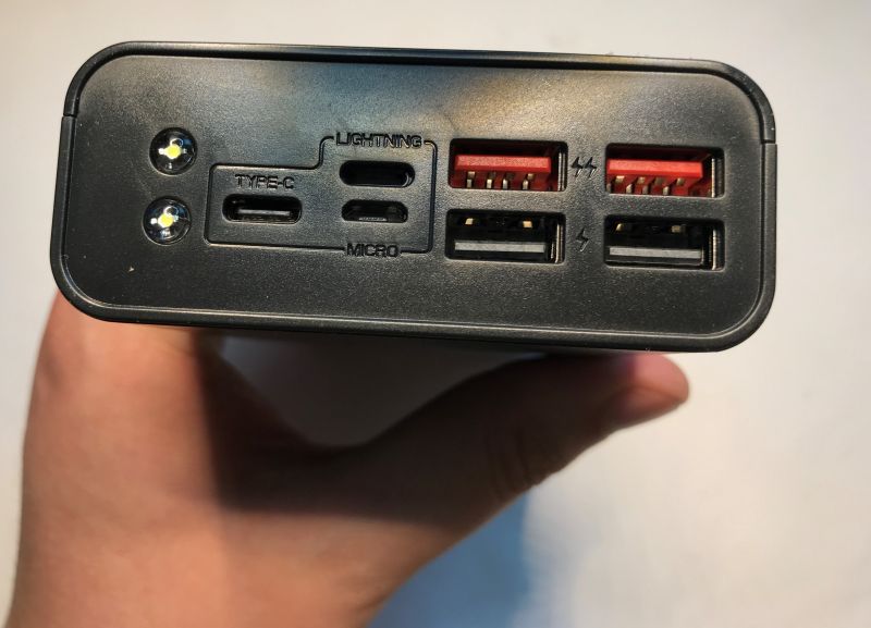 Close-up of a power bank port panel with USB-A, USB-C, Lightning, micro-USB ports and two LED lights