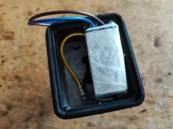 Image of the inside of a black plastic box with several wires and a component inside.