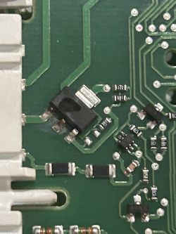 Nahaufnahme einer Leiterplatte mit einem beschädigten schwarzen elektronischen Bauteil.