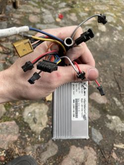 Osoba trzymająca moduł kontrolera z wiązką przewodów i złączami.