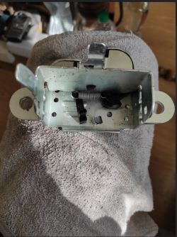 Mechanizm zamka klapy bagażnika z widocznymi elementami wewnętrznymi na ręczniku.