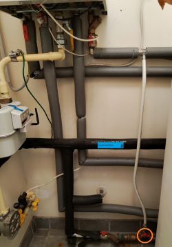 Photo of plumbing installation with pipes and valves. One valve is highlighted in orange.