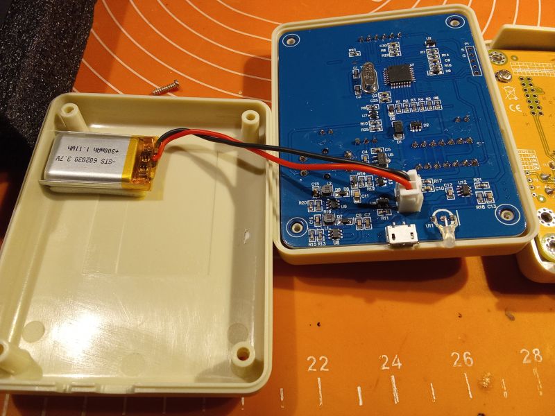 Wnętrze elektronicznego testera z widocznymi elementami układu i baterią