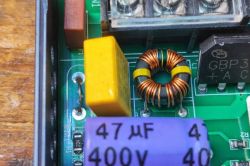 Close-up of a ferrite choke, capacitors, and bridge rectifier on a PCB