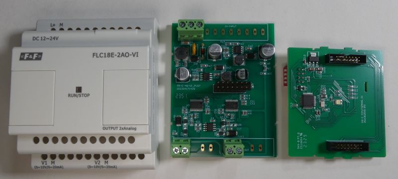 Trzy elementy urządzenia elektronicznego: obudowa modułu FLC18E-2AO-VI firmy F&amp;F oraz dwie płytki drukowane z elektroniką.