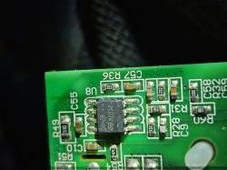Zbliżenie na zieloną płytkę drukowaną z elementami elektronicznymi i oznaczeniami.